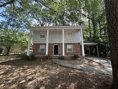 a small brick house with trees in front of it